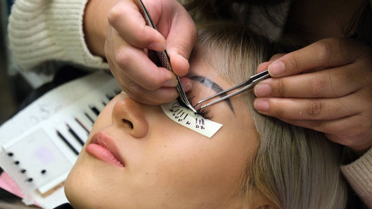 a girl getting lashes done by a professional lash artist